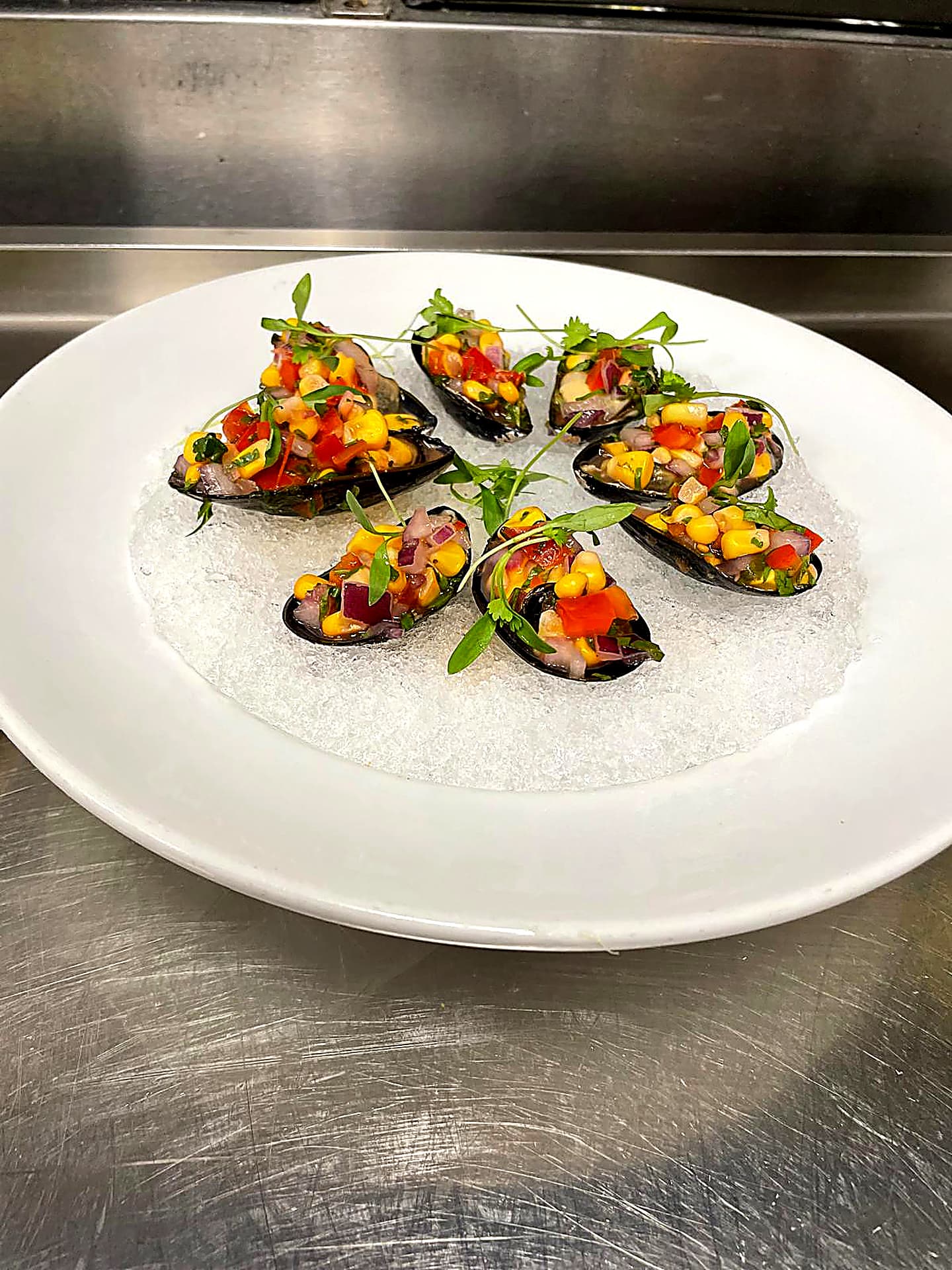 Mussels topped with corn salsa, served on ice