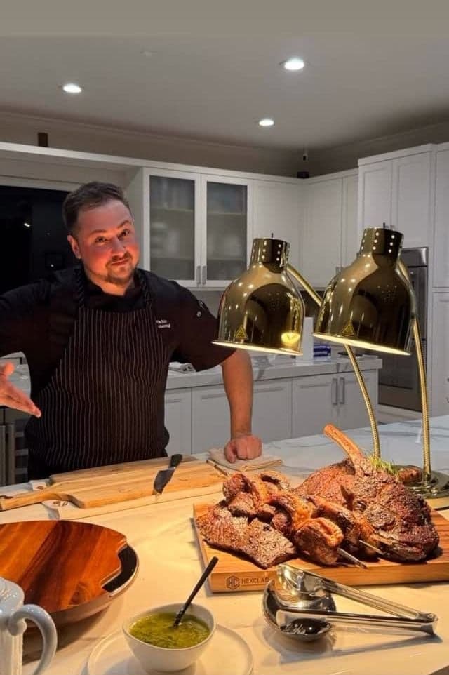 Chef Pablo at a carving station under heat lamps with tomahawk and chimichurri